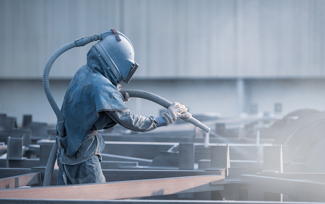 niederdruck-stralen sandstrahl-hs-blasting man_stands_in_protective_suit_and_mask_cleaning